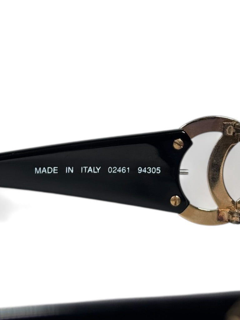 Sunglasses with gold frame and black arm, featuring 'Made in Italy' text.