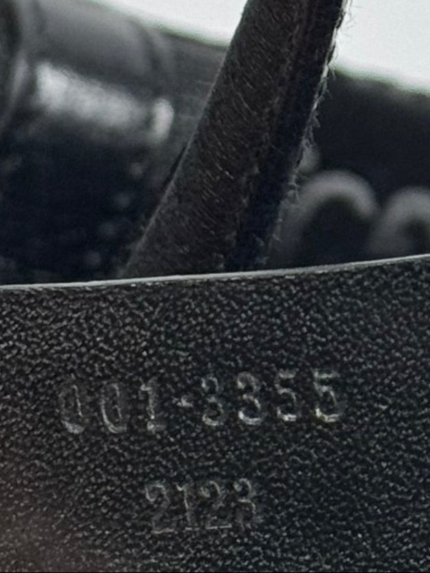 Close-up of a textured black leather tag with numbers on a blurred background