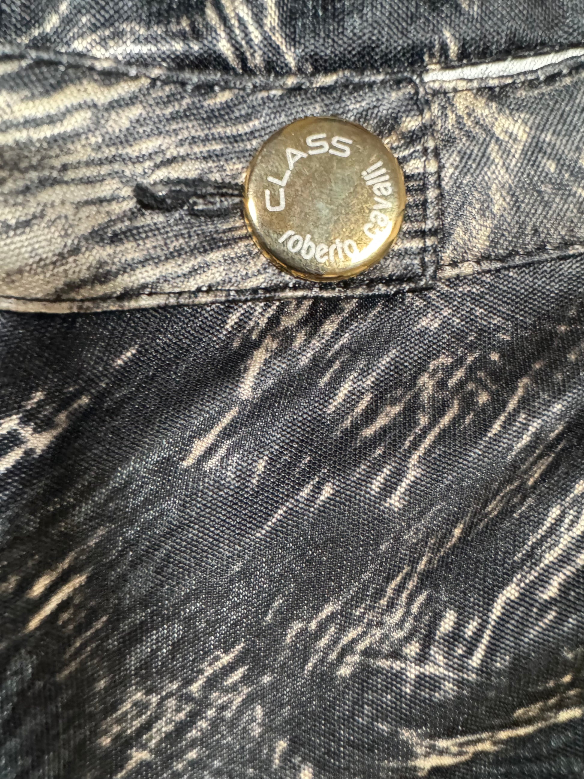 Close-up of a button on a denim jacket with 'Class' branding.