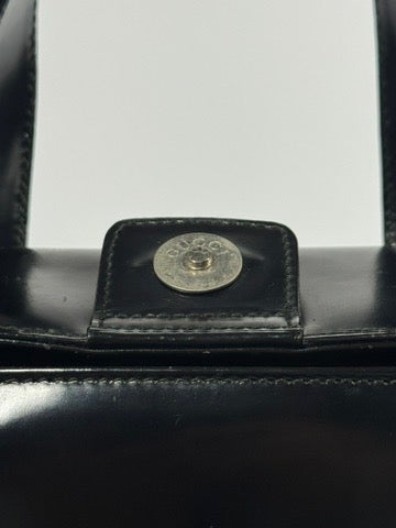 Close-up of a black leather clutch with a decorative button on a white background