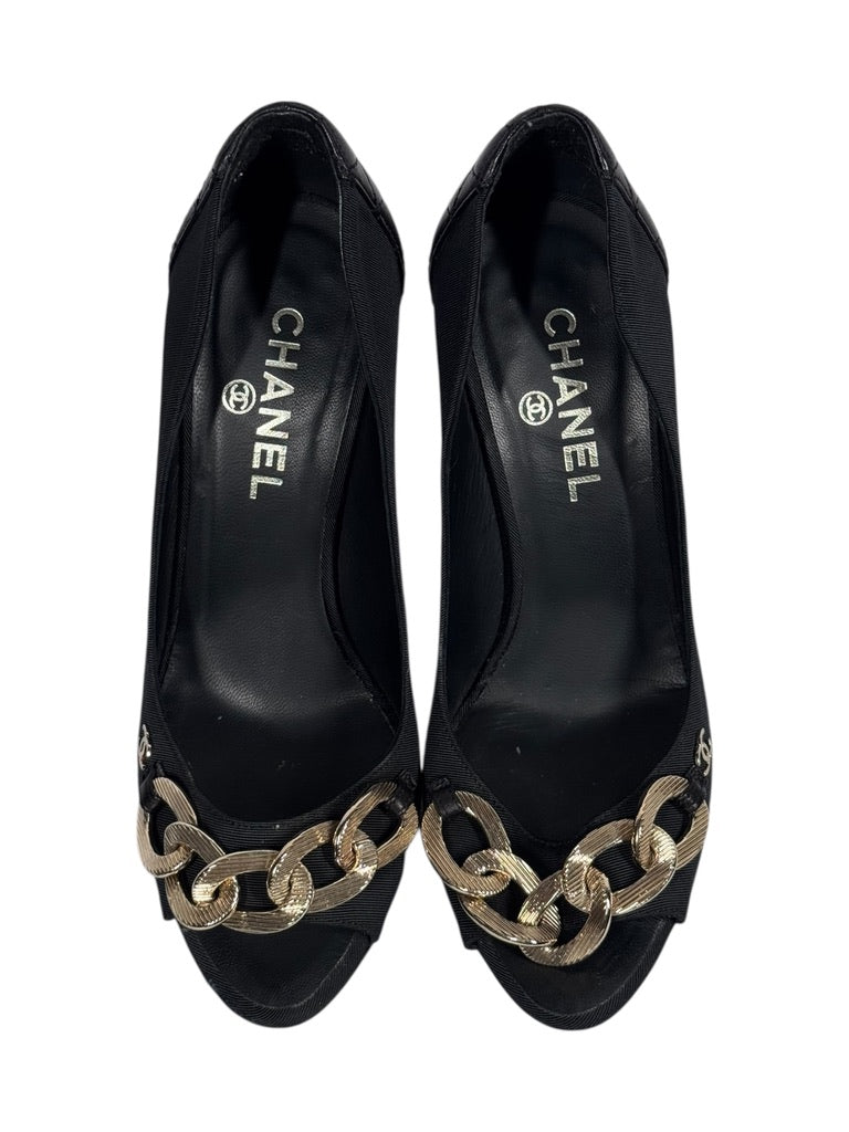 Black Chanel shoes with gold chain detail on a white background