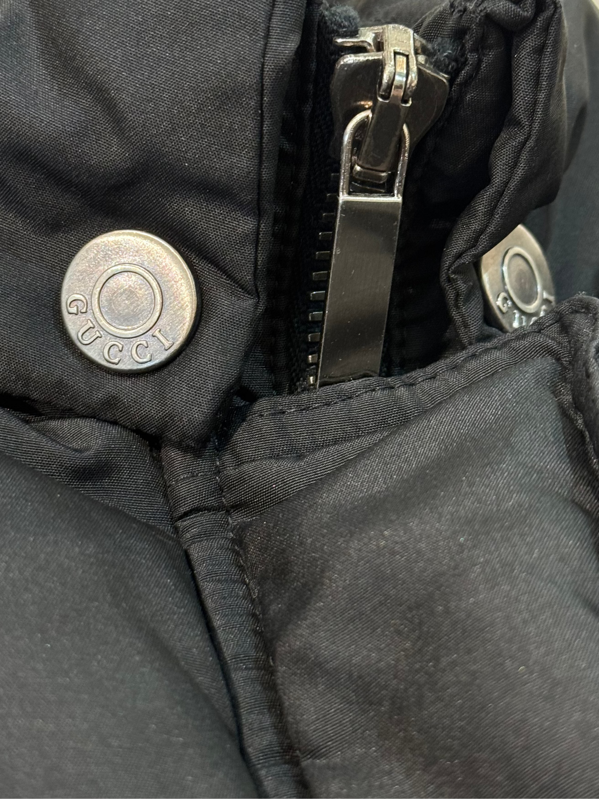 Close-up of a black jacket with zipper and buttons on a neutral background