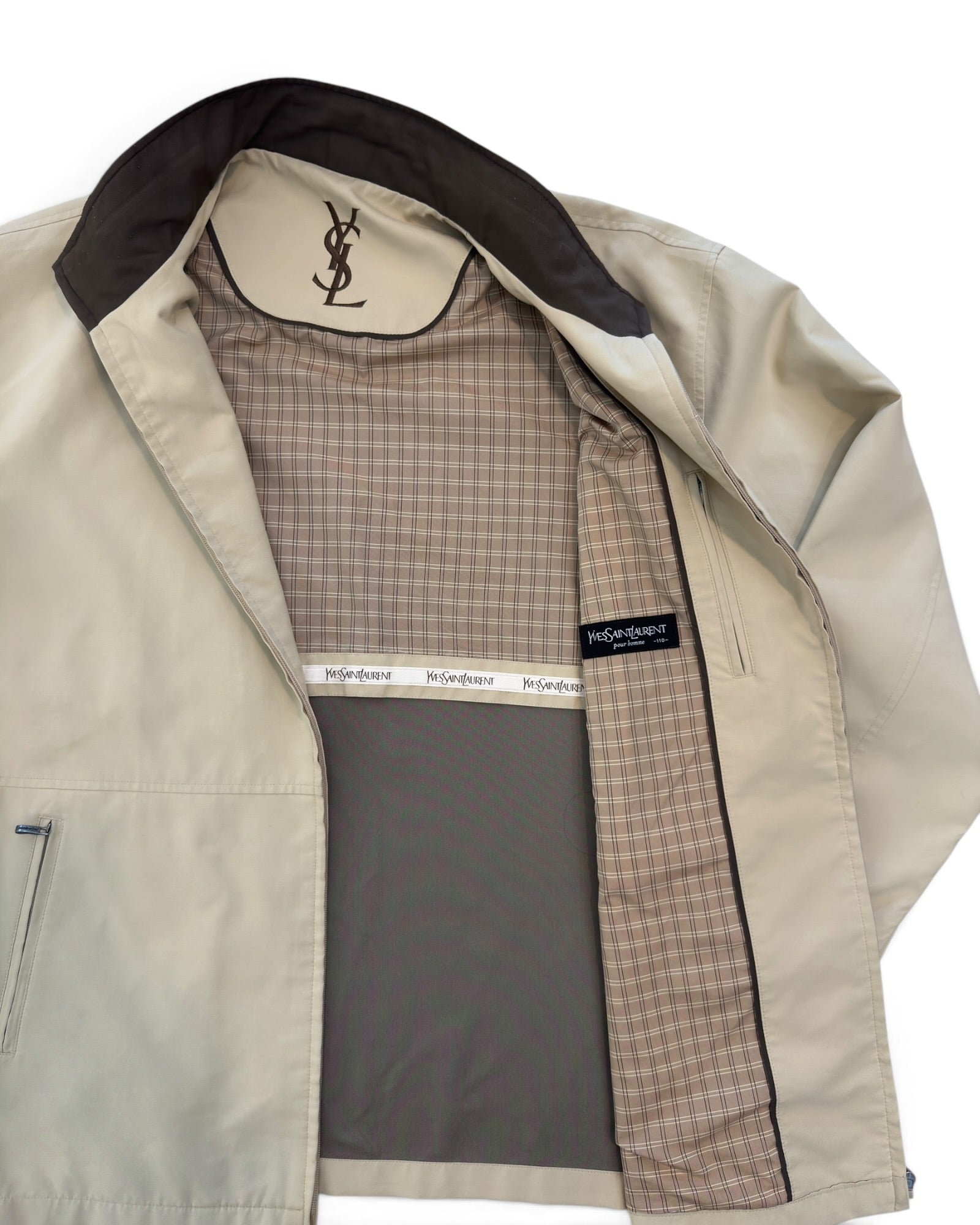 A beige YSL (Yves Saint Laurent) jacket with a dark brown interior lining and a brown-and-beige checkered patterned lining. The YSL logo is visible on the inner collar label, and a YSL brand tag is visible on the chest.