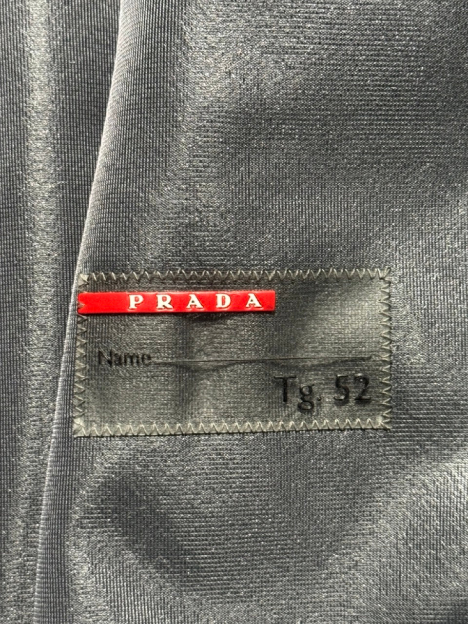 Gray suit jacket with a Prada label on a gray background