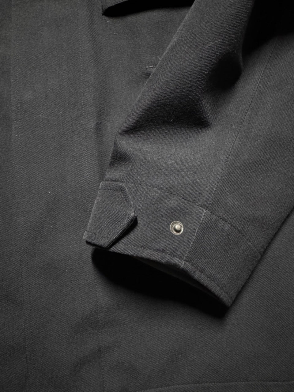Close-up of a dark gray shirt with a button on a matching fabric background