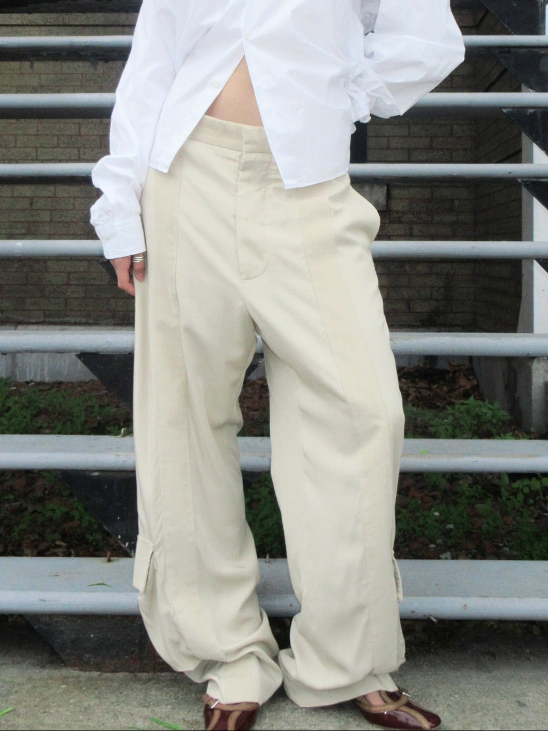 beige bottega veneta pants standing on outdoor steps.