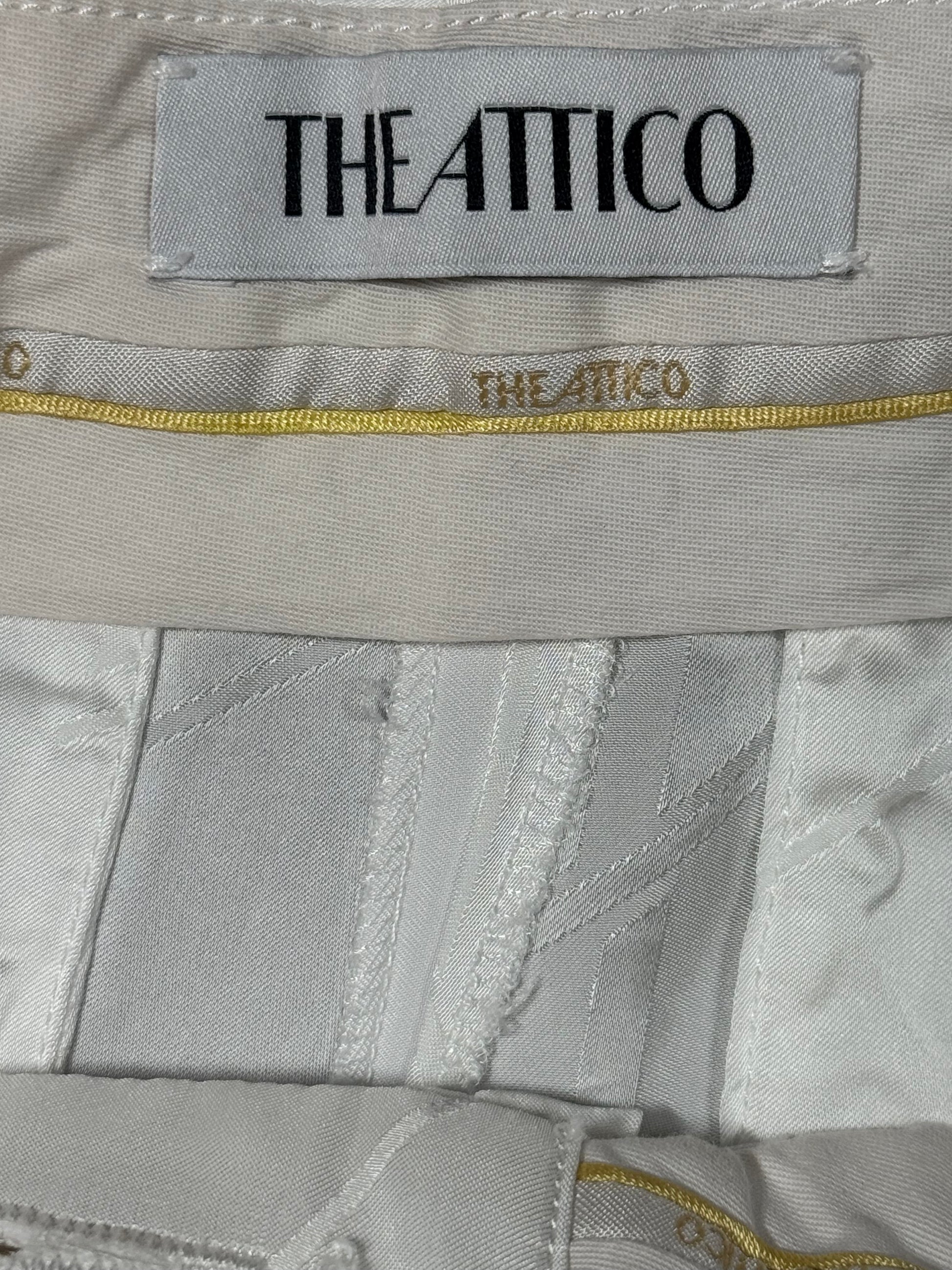 Close-up of 'THE ATTICO' label on a gray fabric background