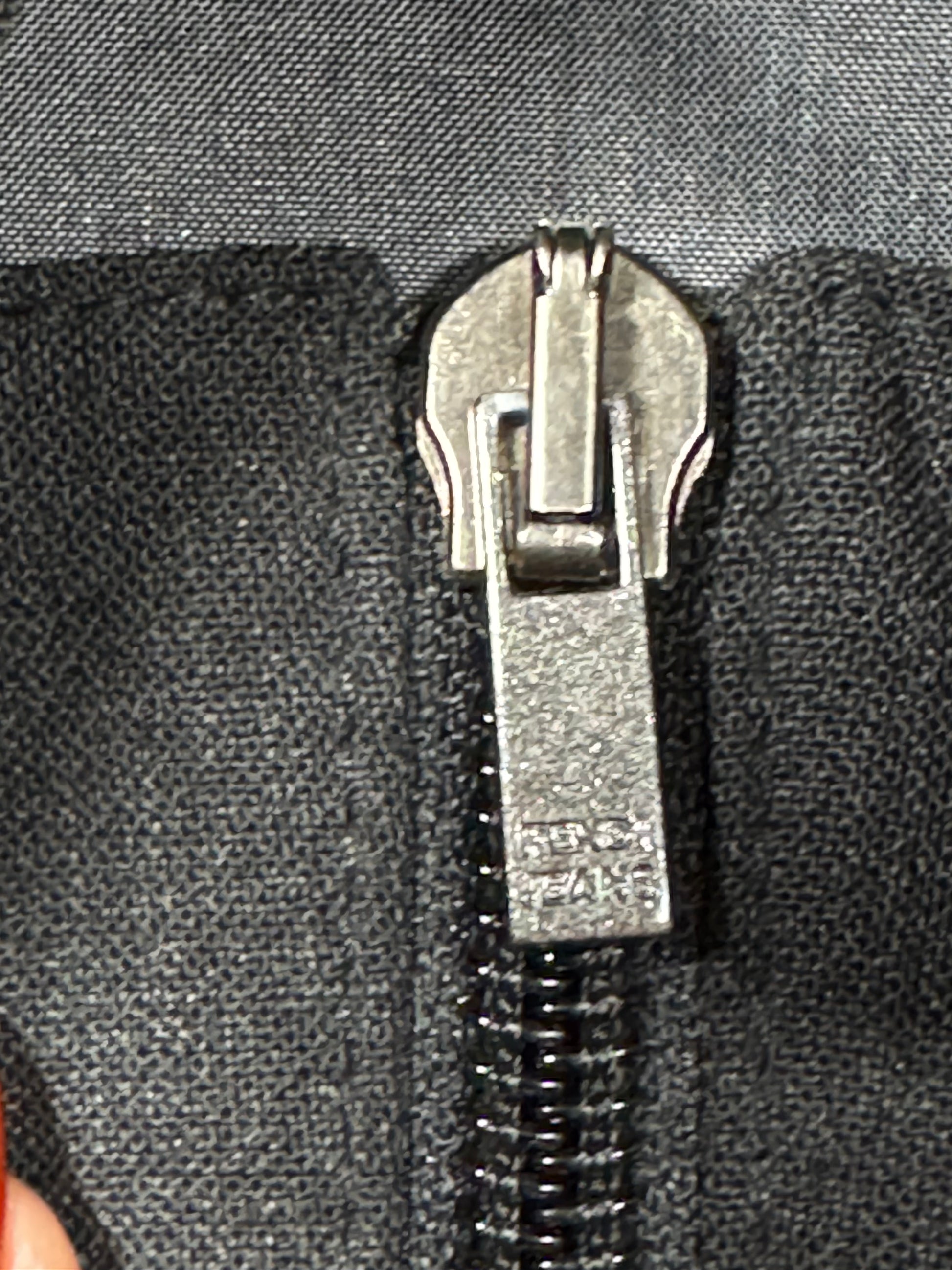 Close-up of a zipper pull on a black fabric background