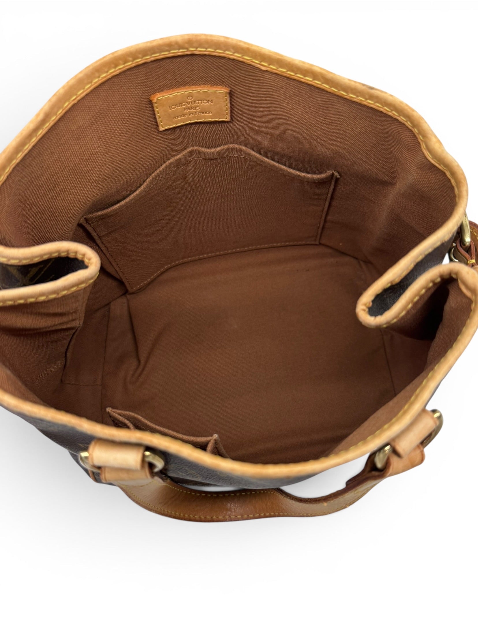 Top-down view of a louis vuitton handbag interior, showing the lining, interior pockets, and tan leather trim and handles against a white background.