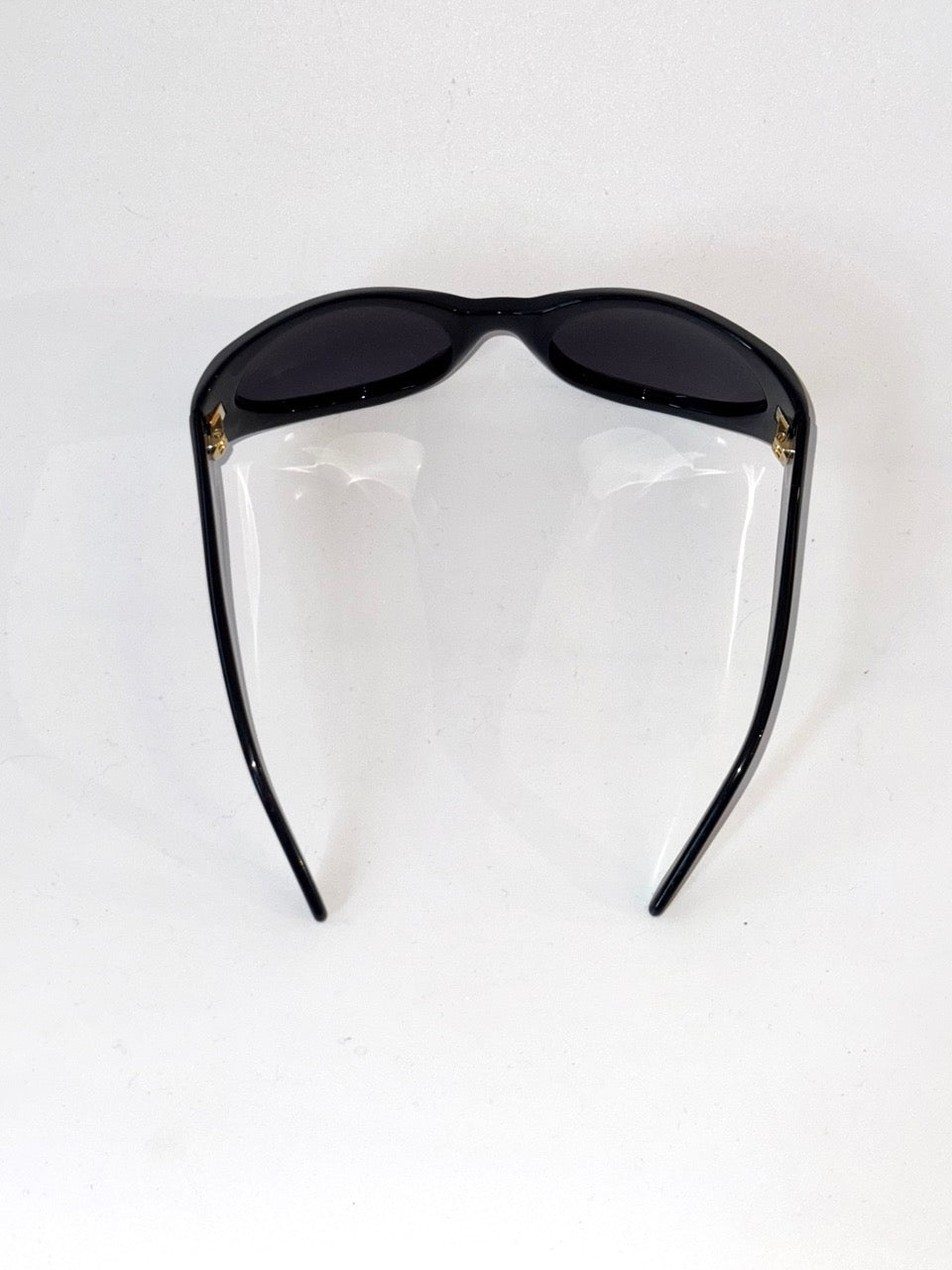 Black sunglasses on a clear stand against a white background
