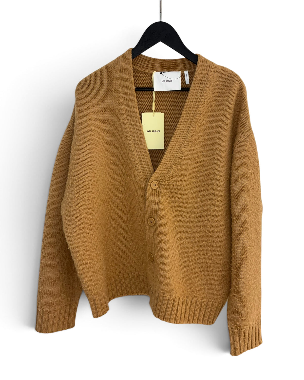 A mustard yellow knit cardigan sweater with a V-neck, three front buttons, and ribbed cuffs and hem, laid flat on a white background with a paper tag attached.