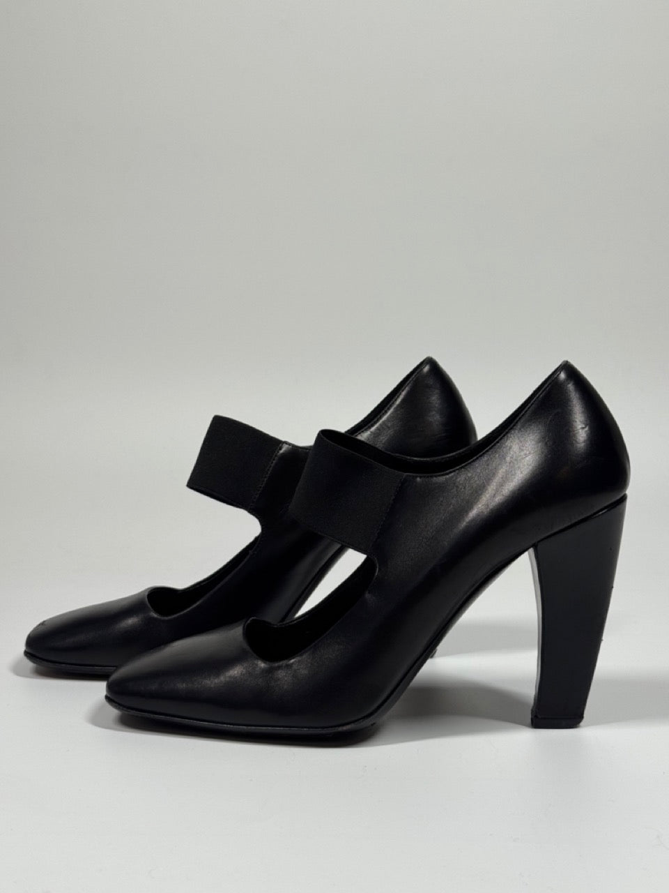 Black high-heeled shoes with a bow on a light gray background