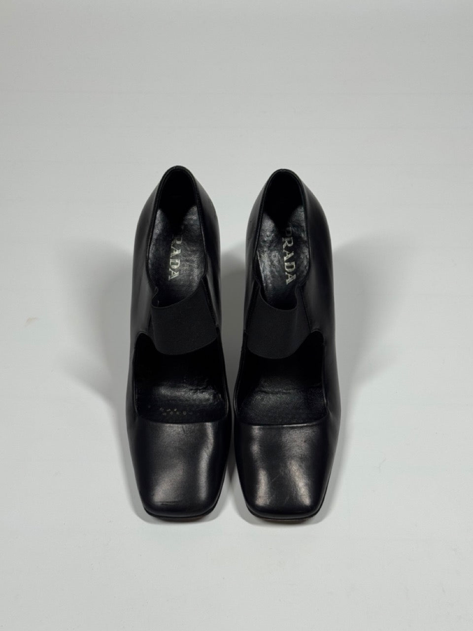 Pair of black high-heeled shoes on a light gray background