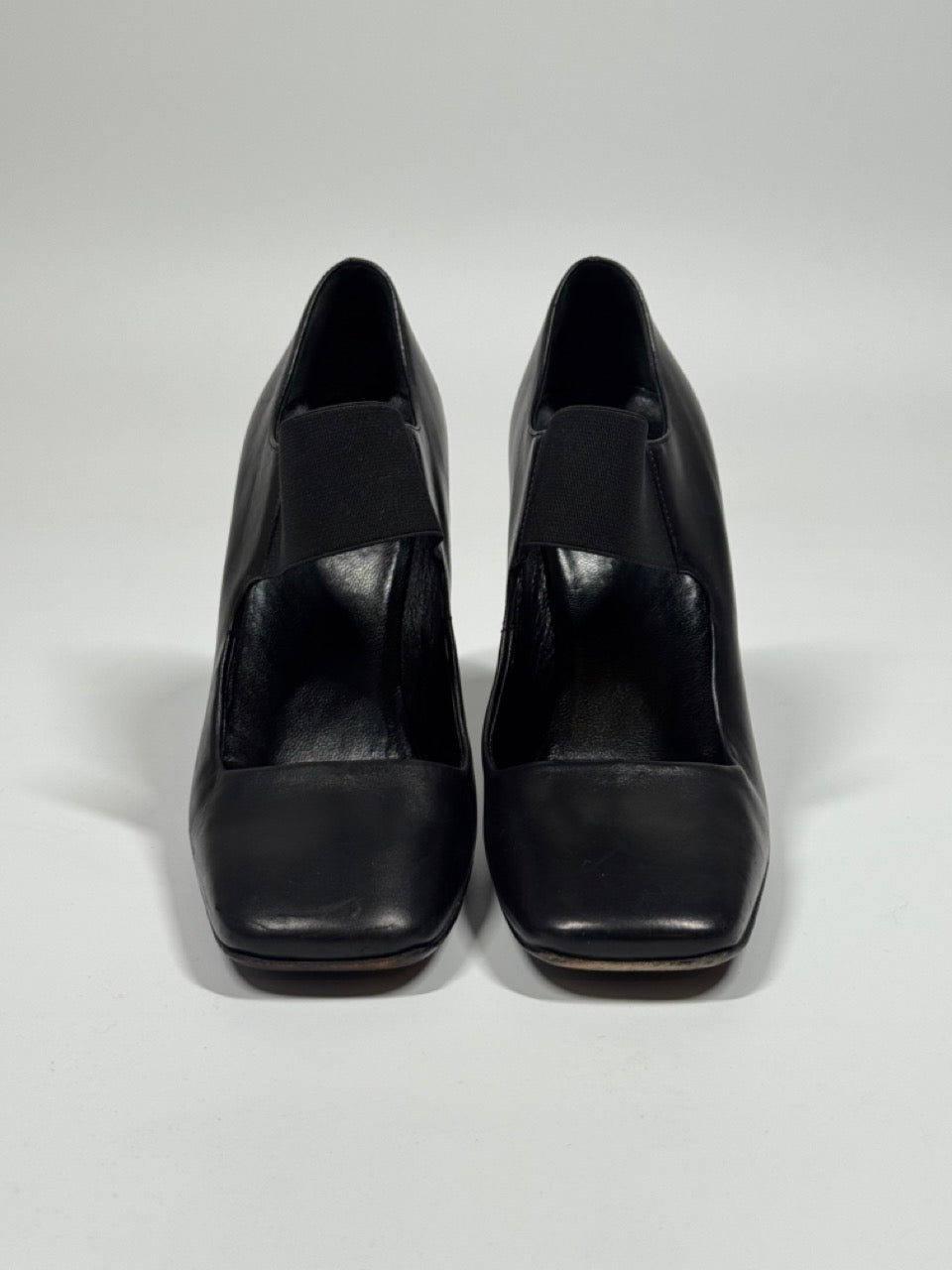 Pair of black high-heeled shoes on a light gray background