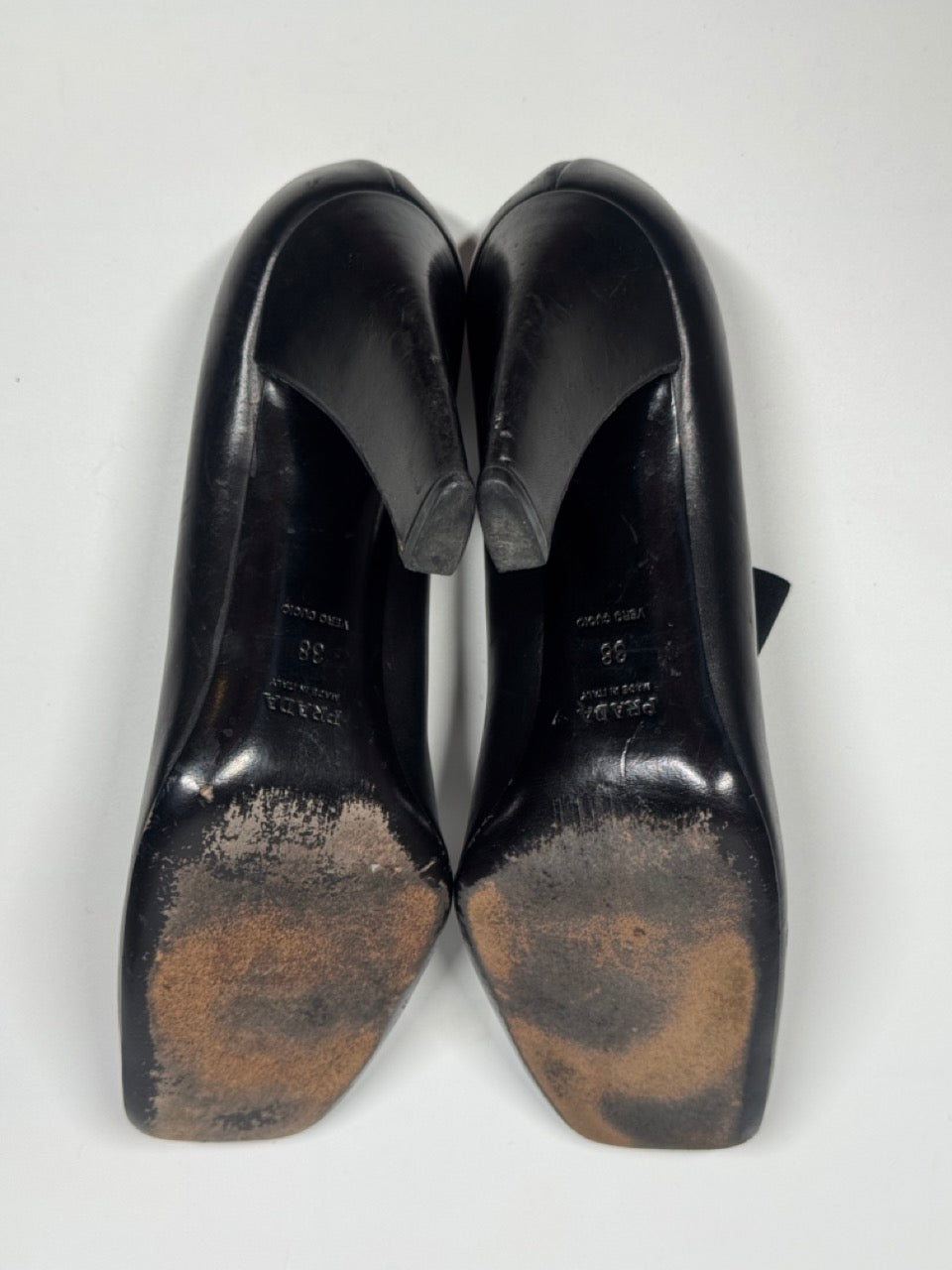 Pair of black shoes with soles showing signs of wear on a white background