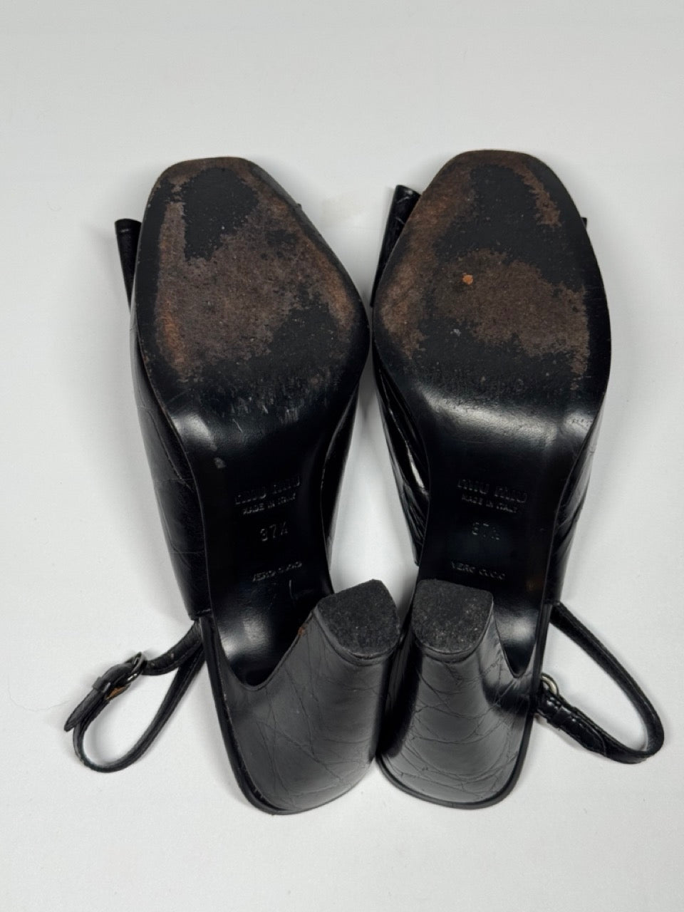 Pair of black leather boots with soles showing wear on a light gray background