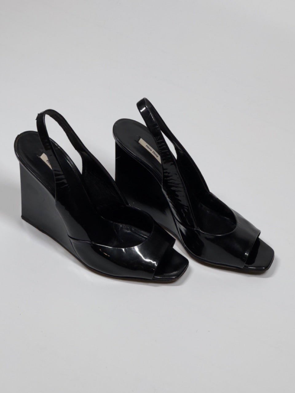 Black wedge sandals on a light gray background