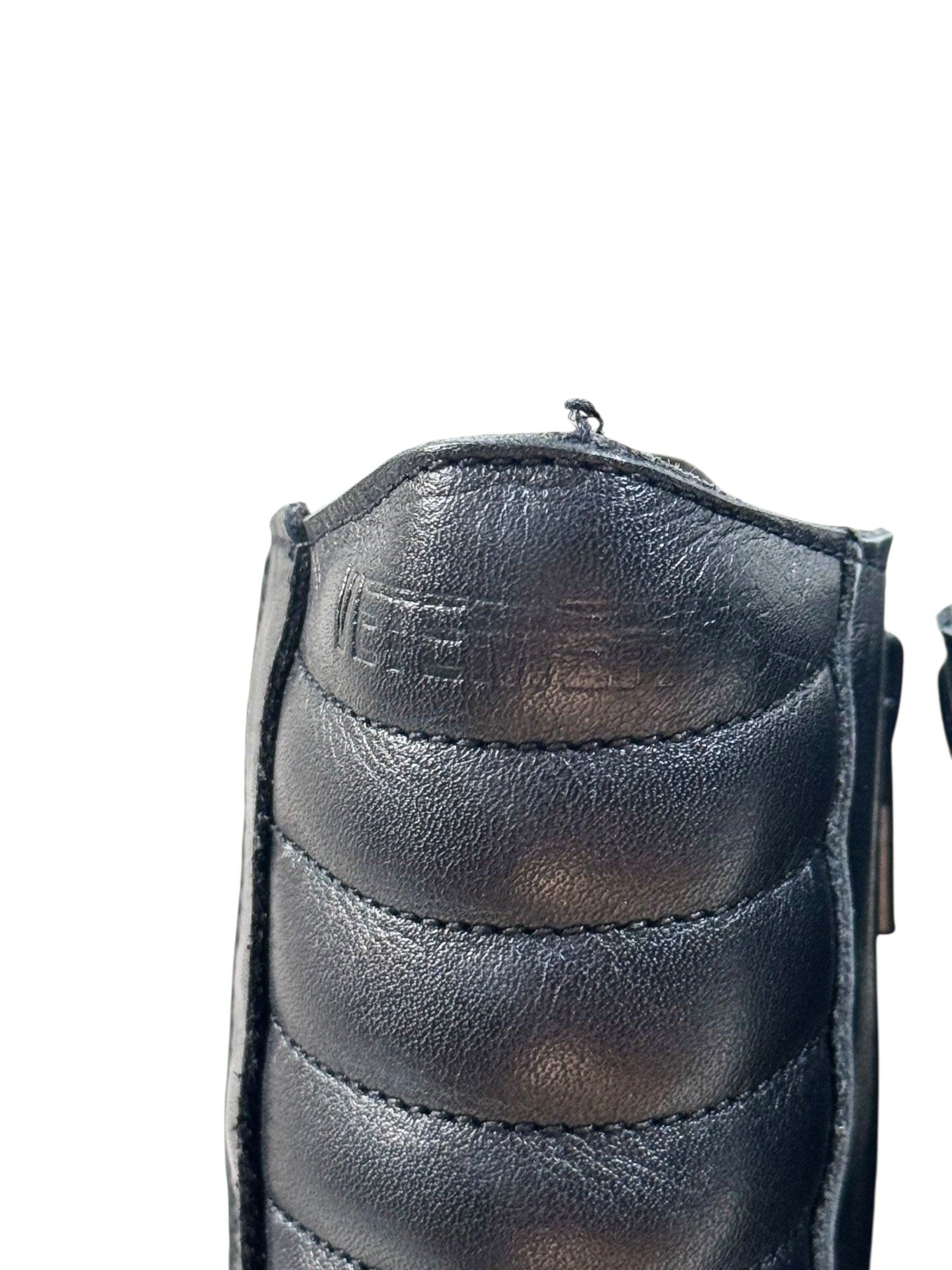 Close-up of a black leather boot with visible stitching on a white background