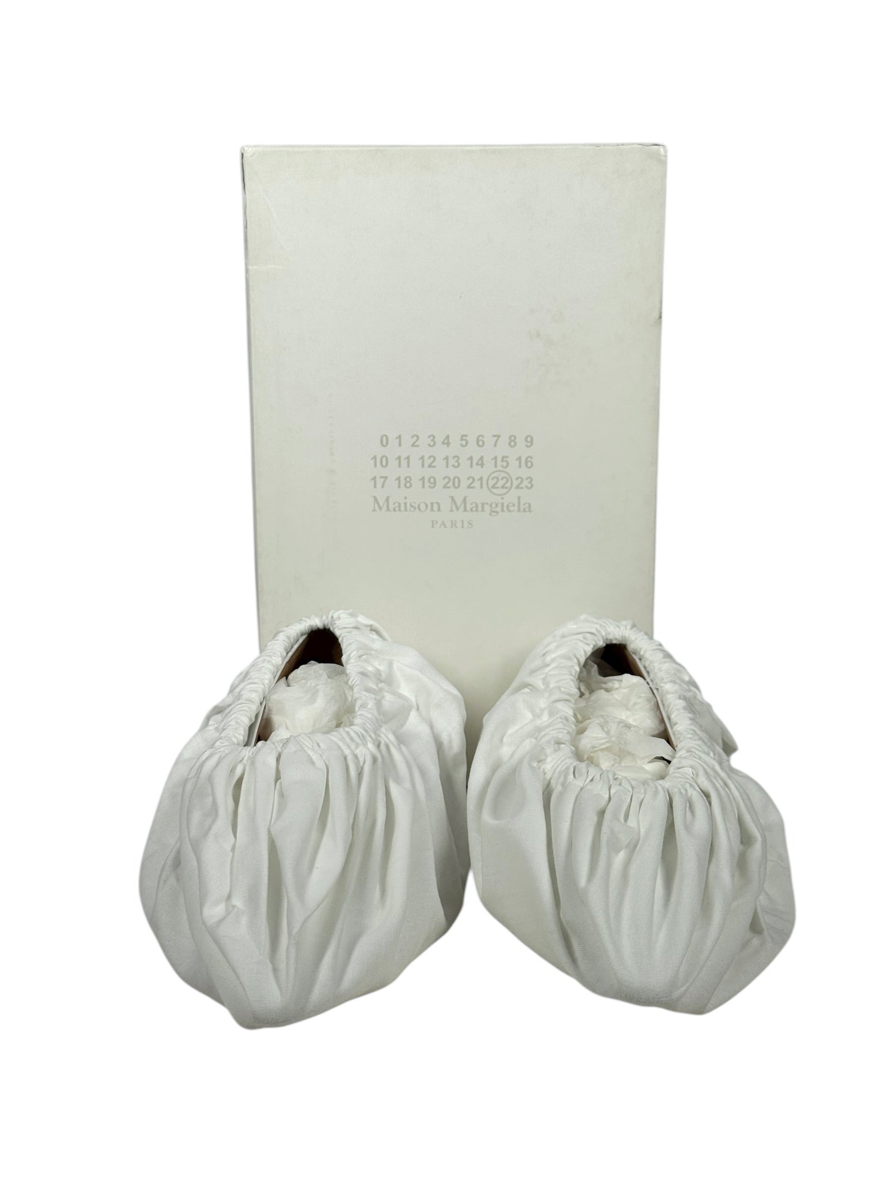 Two white shoe covers with a branded  margiela box on a white background