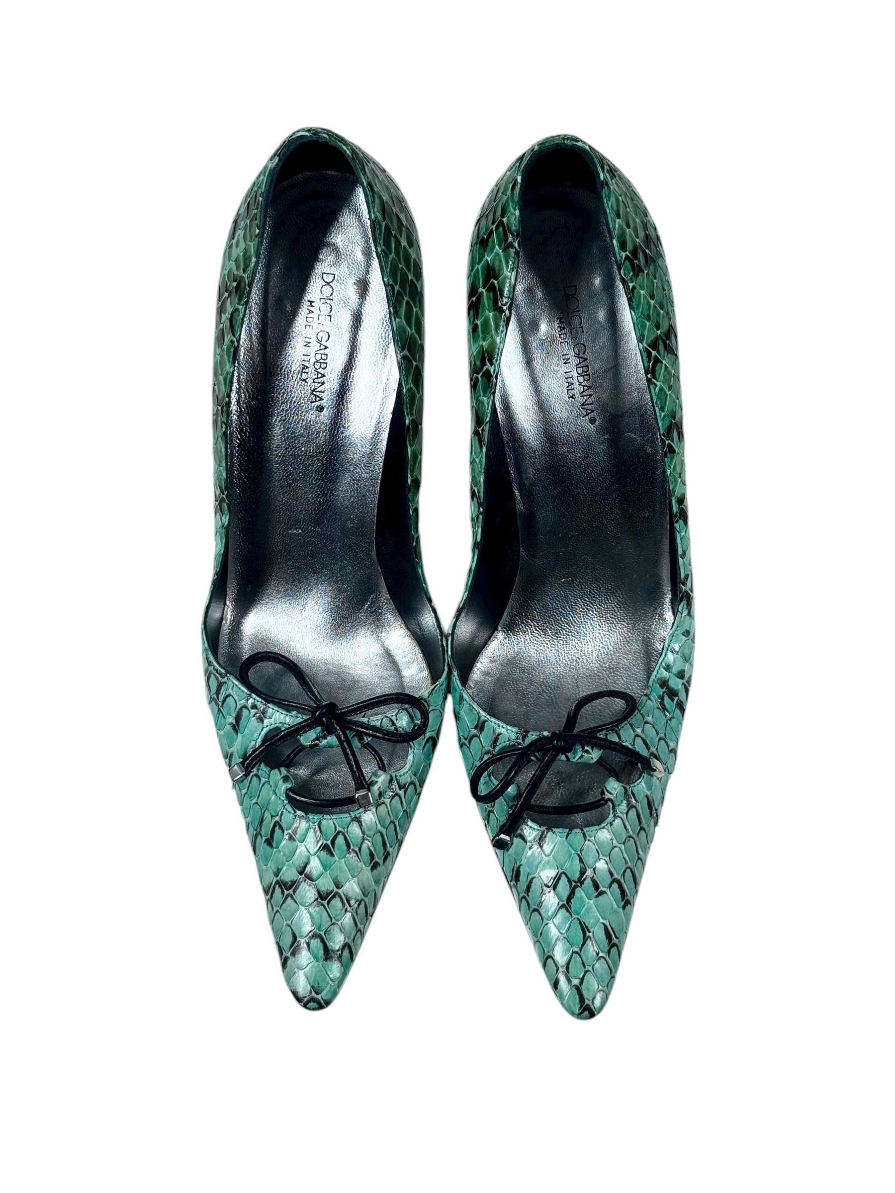 Pair of green snake skin high heels with black laces on a white background
