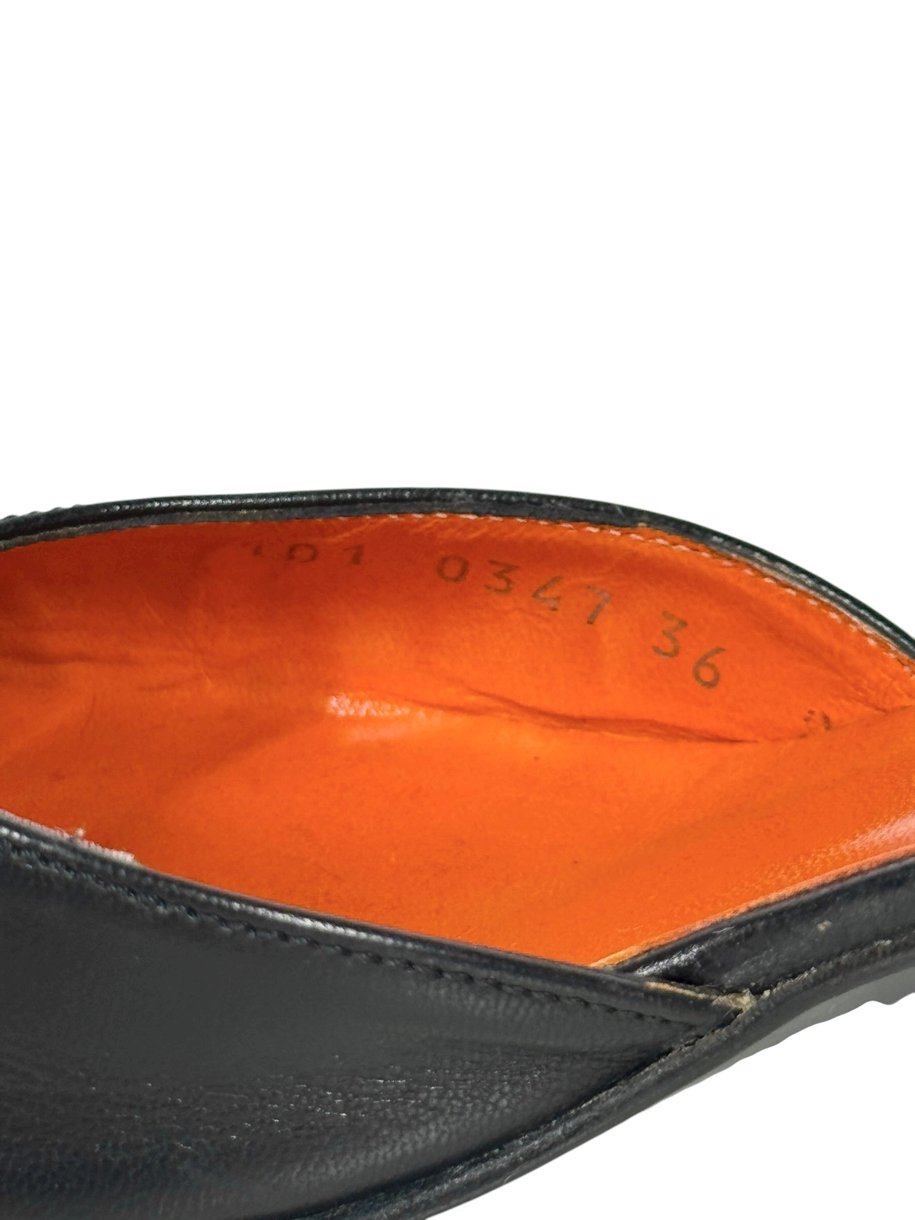 Close-up of a black leather shoe sole with orange lining on a white background