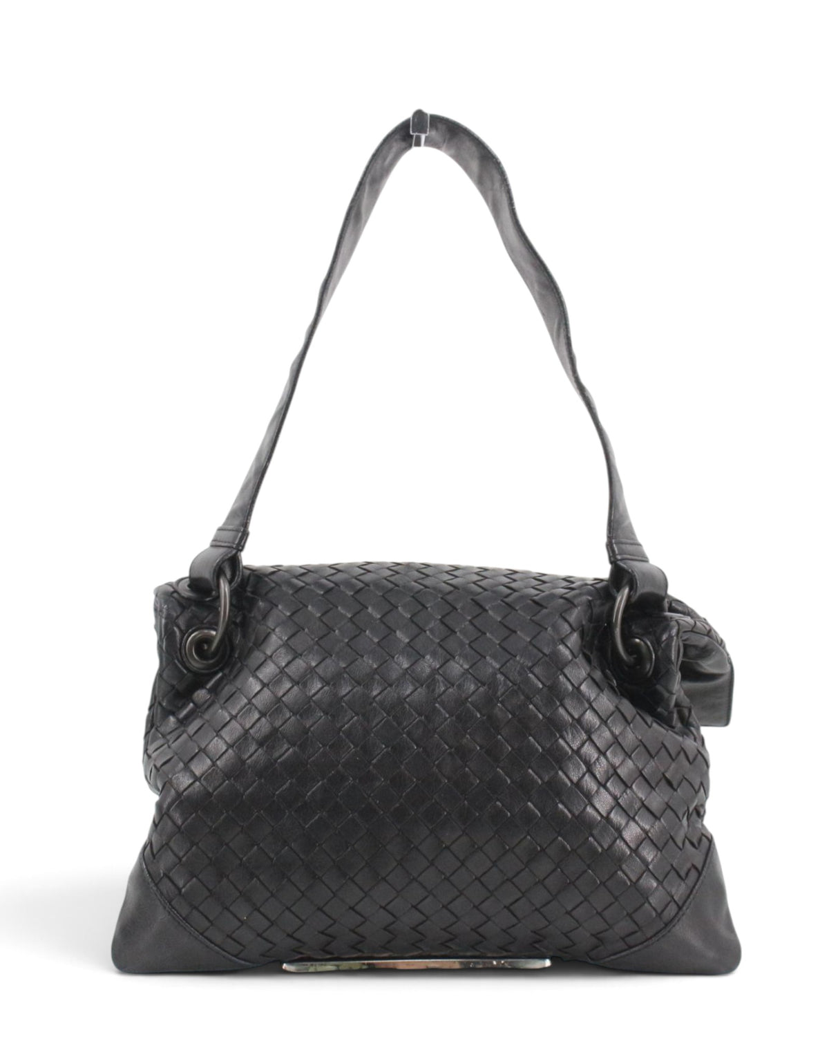 A black woven leather bottega shoulder bag with a flap top and long strap, shown on a plain white background with a small rectangular mirror placed beside it.