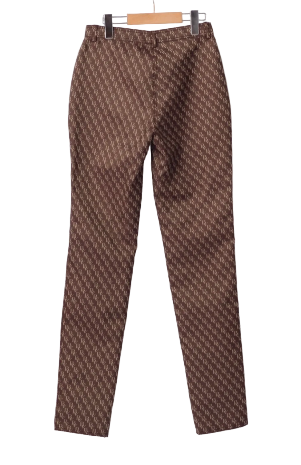 A pair of brown pants with a repeating geometric monogram pattern, hanging on a wooden hanger against a light gray background.